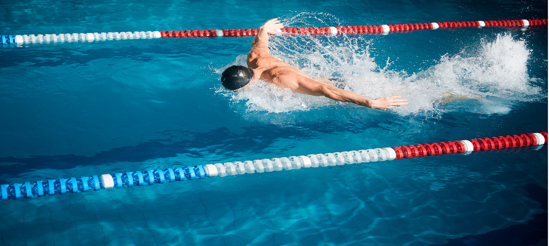 Swimmer performing freestyle stroke in pool.